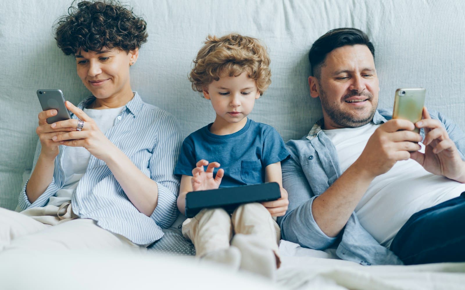 A family sitting together, each absorbed in their own phone or tablet