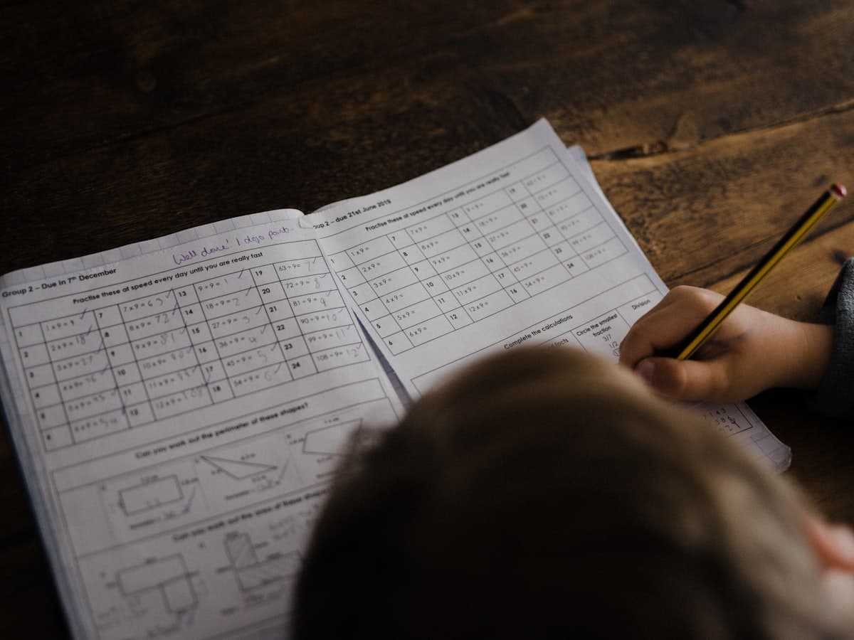 A child working through a worksheet with a pencil